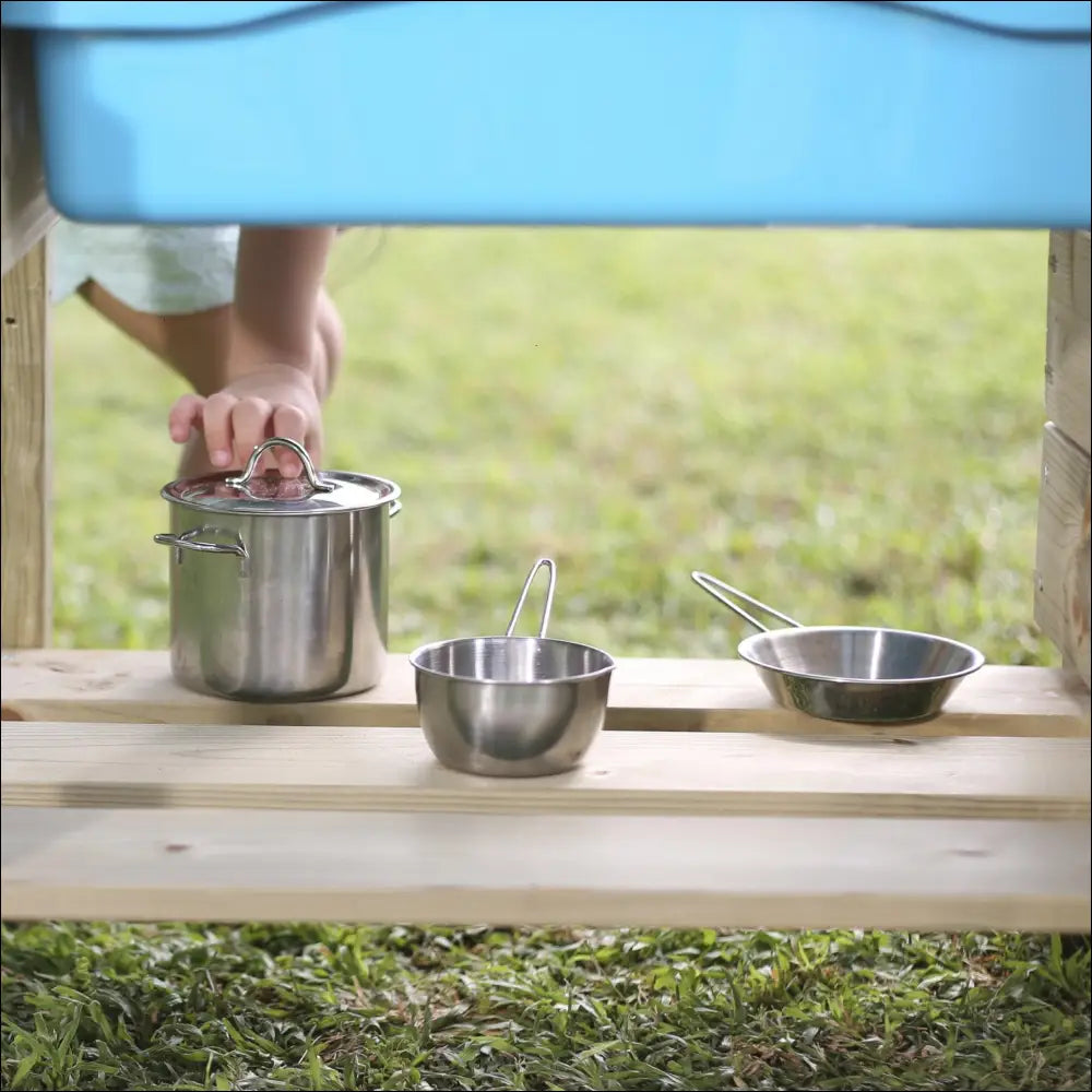 Juego de ollas y sartenes de acero inoxidable sobre una superficie de madera con Exterior Chef Junior